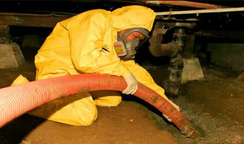 Worker in a protective suit clearing sewage water with a hose