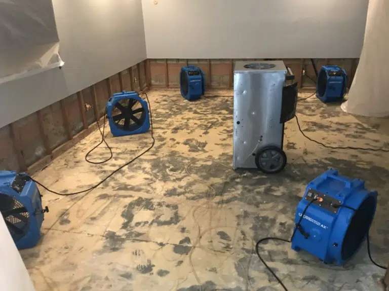 Air movers and a dehumidifier drying a water-damaged room
