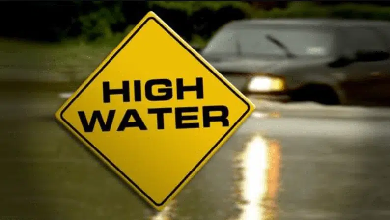 High water warning sign beside a flooded road